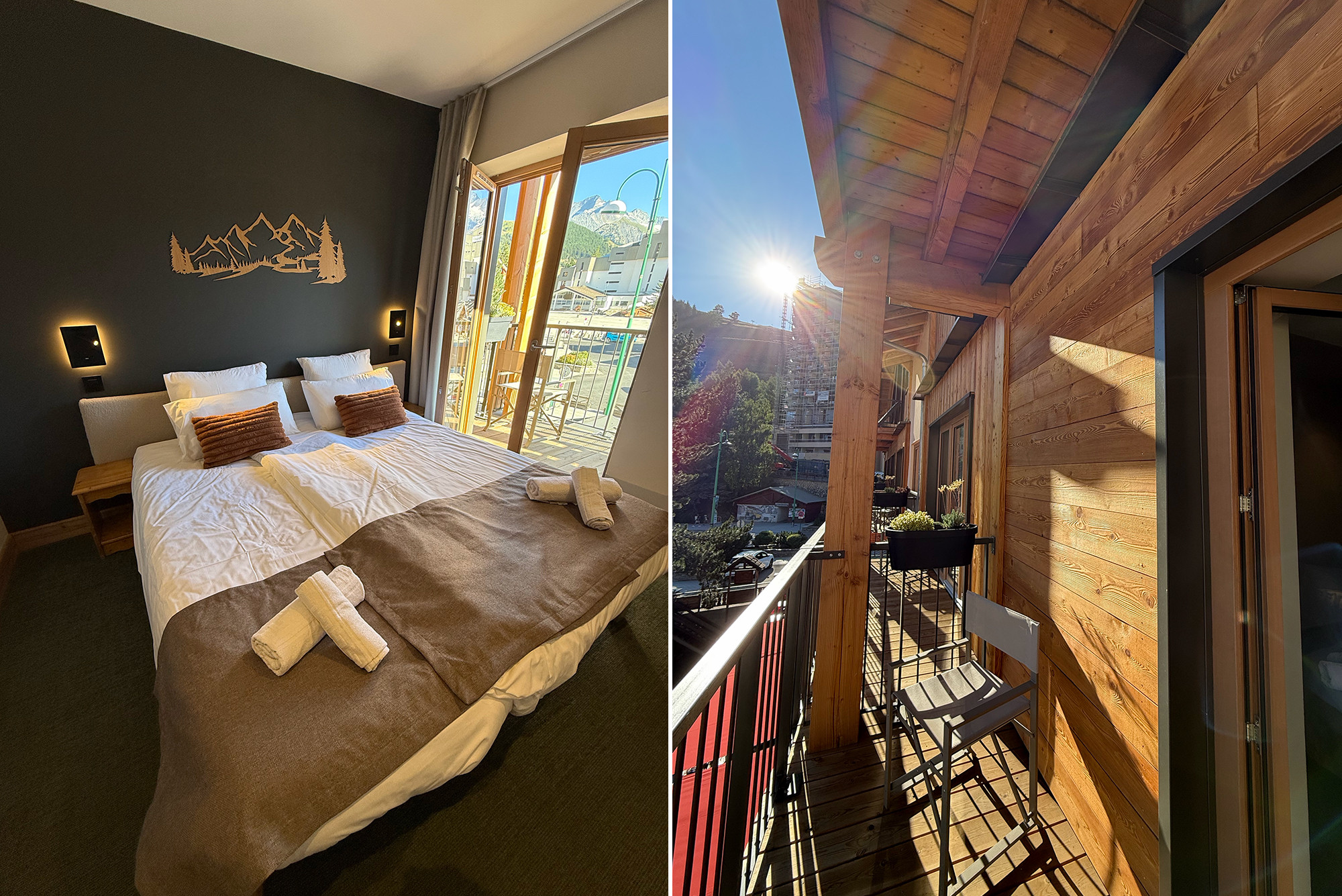 Interior hotel room with a large bed, white linens and brown throw, dark accent wall featuring a mountain silhouette, and an open balcony door to view outside.
