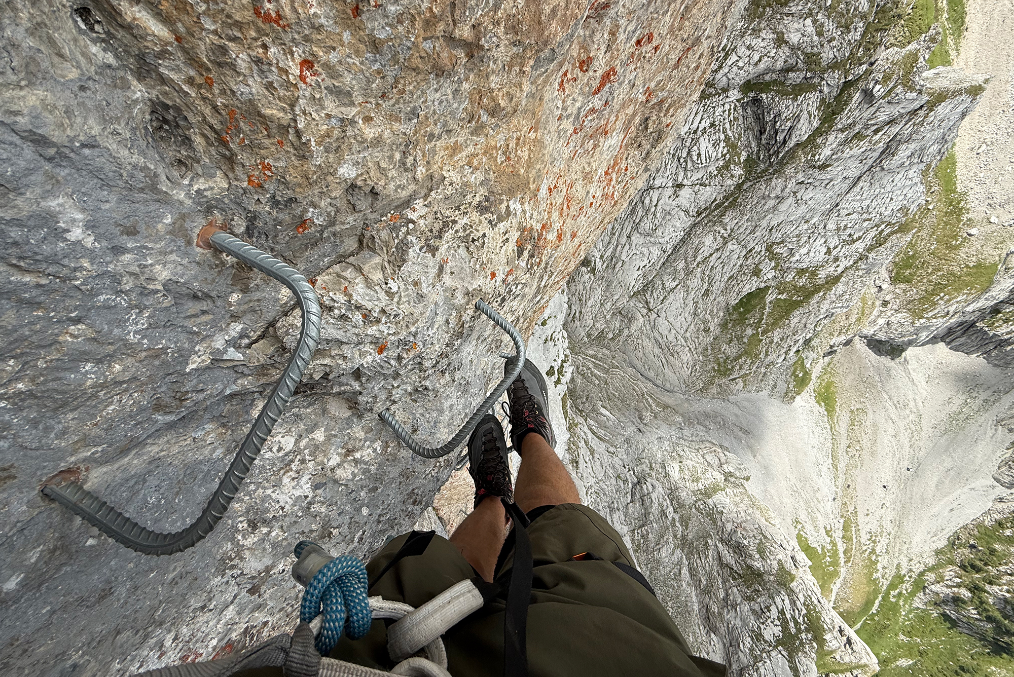 Climber's feet and climbing rope on a rugged rock face with metal rungs, viewed from the climber's harness point of view.]}]}''? Wait need proper JSON. Ensure array of strings. Provide multiple options. Let's craft correctly.